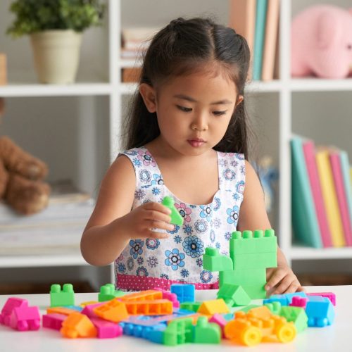 Little Asian girl playing with plastic cubes